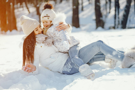 年轻和时尚的妈妈与长黑发玩与她的小可爱的女儿在冬季雪公园