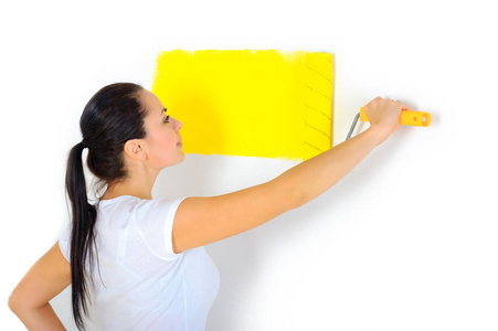 女画家用明亮的黄色用滚子画墙面