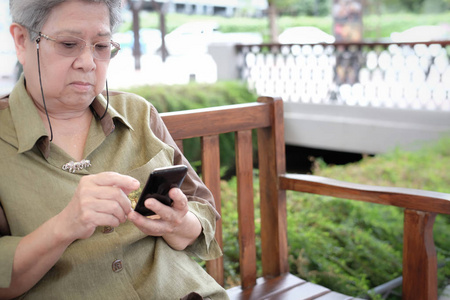 手持手机的老年妇女。老年女性短信信息, 使用智能手机户外应用