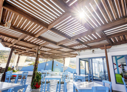 海滩咖啡厅和餐厅的蓝色和白色的桌子和椅子在希腊风格, 太阳的光芒。餐厅内饰