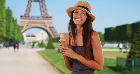 美丽的年轻旅游妇女拿着冰淇淋锥附近埃菲尔铁塔