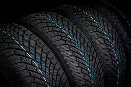 冬季汽车轮胎在黑色背景查出的行