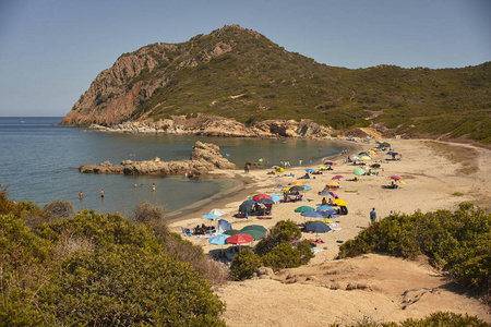 撒丁岛南部的海滩 卡拉萨菲古 插入一个自然的海湾充满游客与雨伞度假