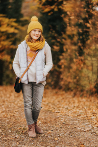 秋天的肖像可爱的青春期女孩1011 岁, 穿着灰色的背心, 一套黄色的帽子和围巾