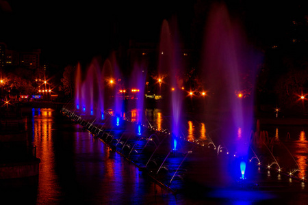在远东城市哈巴罗夫斯克, 发光的五颜六色的照明喷泉。夏季结束时的秋季歌唱喷泉表演