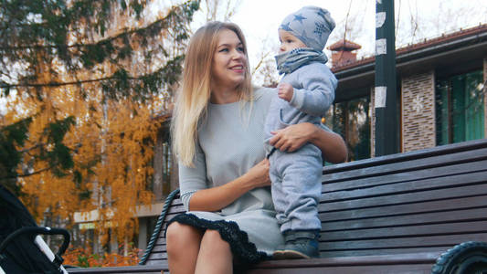 年轻的母亲坐在长凳上抱着一个婴儿。中枪