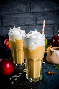 香料焦糖苹果或苹果派奶昔, 有机秋季水果鸡尾酒与生奶油, 在黑暗的背景下, 与苹果, 叶子, 焦糖酱和温暖的毯子。复制文本空间