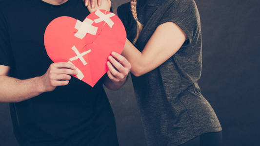 破碎的心痛苦的爱情观。几个女人和男人手里拿着纸红色心用石膏绷带固定。在关系中的裂痕