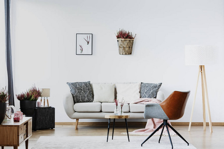 灰色扶手椅靠近沙发与客厅内的垫子与海报和希瑟在白色的墙上