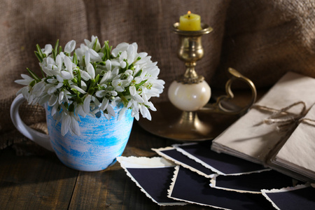 组成与美丽的雪莲花，在花瓶 蜡烛 旧信和麻布背景上木制的桌子上的照片