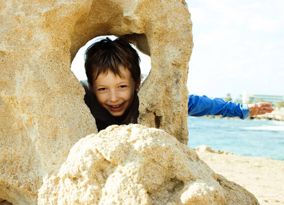 小可爱男孩在玩石头海海岸大拇指上