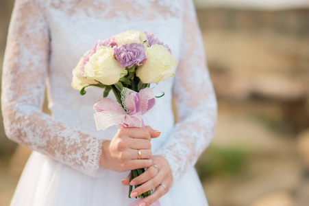 穿着白色连衣裙的新娘捧着结婚花束