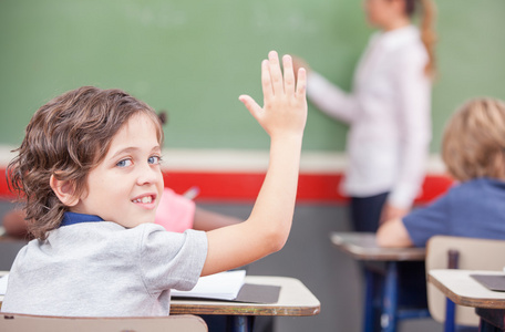 幸福小学男孩举起他的手在教室里