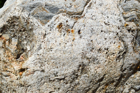 天然天然雕刻的质地坚硬粗糙粗糙的粗纹理矿物灰褐色石卵石在岩石的墙壁上。石材背景