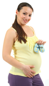 年轻的怀孕女子捧着孤立的白色衬底上的蓝婴儿鞋
