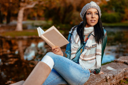 年轻女子读本书在秋天公园
