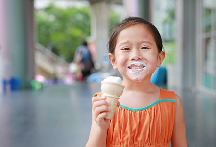 快乐的小亚洲孩子女孩喜欢吃冰淇淋锥与染色周围她的嘴