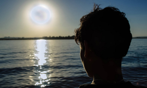 日落的照片密切注视着一个男孩在湖畔