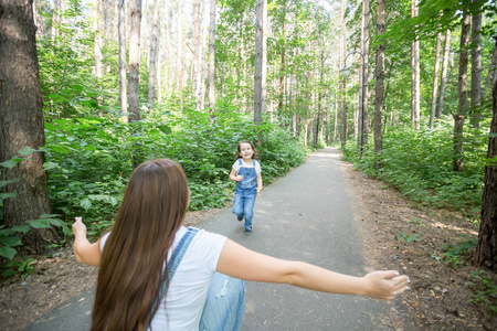 自然, 家庭, 人的概念可爱的小女孩和年轻女子在美丽的森林。女儿跑到母亲