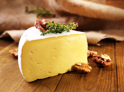 美味卡门培尔奶酪奶酪配百里香和坚果，木制的桌子上