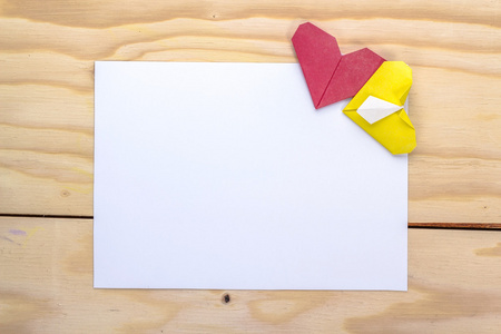 情人节礼物卡与折纸黄色和红色爱心木制的桌子上