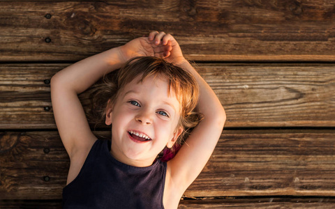 一个小红头发的女孩的肖像, 躺在木地板上复制空间。微笑着四岁的女孩, 美丽的蓝眼睛。概念快乐童年