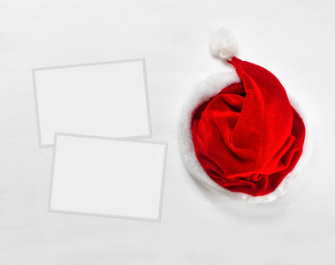 明亮的红色圣诞老人帽子与纸框架的文本或照片的木质背景。顶部视图平面放置组对象