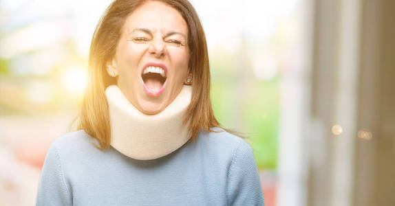 受伤的妇女戴着颈托项圈压力重重, 惊恐万分, 大喊恼怒和沮丧。不愉快的手势。烦人的工作让我发疯