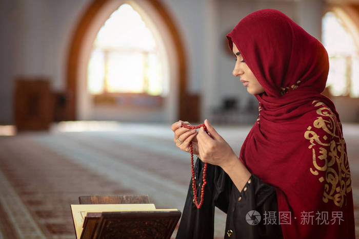 在清真寺与古兰经祈祷的年轻穆斯林妇女