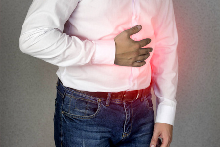 一个穿白衬衣的男人抱着腹部, 腹痛, 胃灼热, 特写
