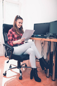 年轻的微笑的女企业家坐在办公室里看财务报告