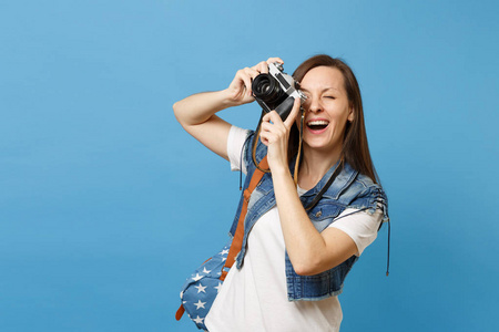 年轻快乐的女学生的肖像与背包张开嘴拍摄复古复古照片相机隔离在蓝色背景。大学教育。复制广告空间