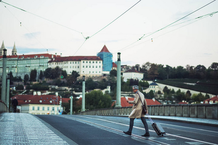 在布拉格市, 一位拿着智能手机和手提箱横穿马路的商人