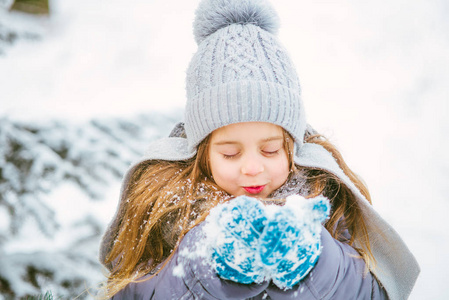 可爱的小女孩微笑和玩在冬天与雪