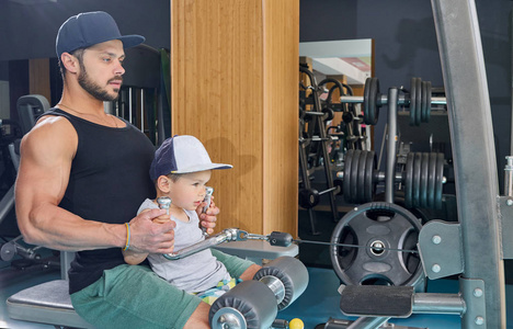 爸爸和小儿子的侧面观看在体操模拟器做胳膊锻炼