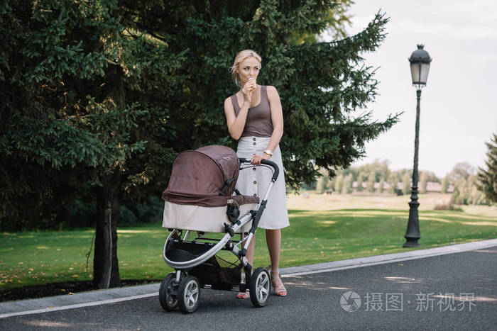妈妈带着婴儿车走 在公园吃冰淇淋