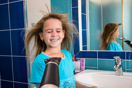 一个小女孩在浴室里用吹风机吹发
