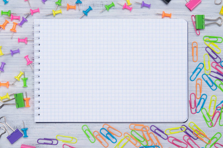 一个空白的笔记本, 在五颜六色的剪辑和按钮的背景下, 有刻字的空间