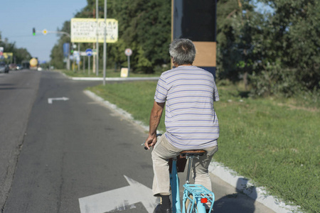 一个中年男子骑着一辆城市自行车沿着公路行驶。