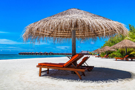马尔代夫2018年6月24日 夏季日在马尔代夫热带海滩上的木制日光浴和雨伞