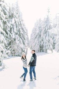年轻夫妇走在下雪的冬天森林, 一起度过圣诞假期