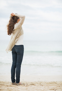 在寂寞的海滩上的毛衣的女人