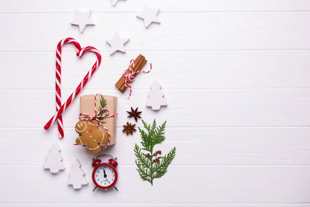烘焙时间。为假期做准备。圣诞节或新年背景与饼干, 丝带, 糖果棒, 圣诞饰品, 礼品盒, 松果和冷杉树枝红色闹钟
