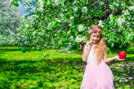 快乐的小可爱女孩在繁花似锦的苹果树园