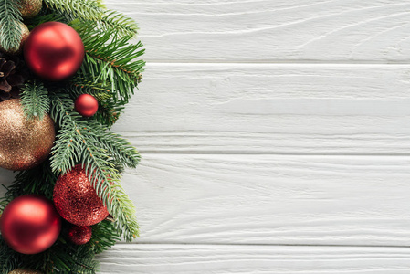 在白色的木表面上的红色圣诞玩具花圈的顶部视图