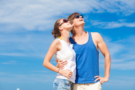 快乐的年轻夫妇，在太阳镜上海滩微笑着望着天空中的特写