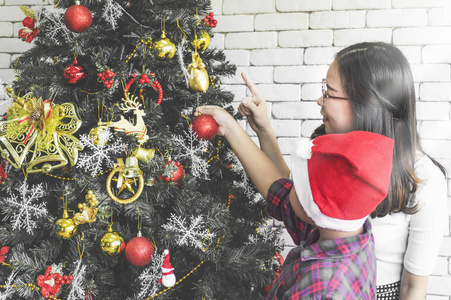 圣诞快乐, 节日快乐妈妈和儿子在室内装饰圣诞树。爱的家庭在室内