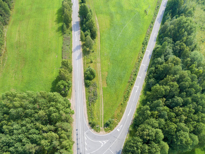 公路鸟瞰图。一条乡间小路的鸟瞰图。车经过。空中公路。空中鸟瞰飞行。从上面捕获的无人机