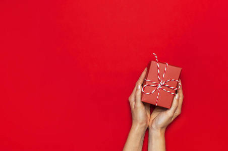 礼品盒与装饰花边在女性手在红色背景顶视图平放置。节日概念新年或圣诞礼品盒礼物圣诞节假期祝贺背景与文字空间