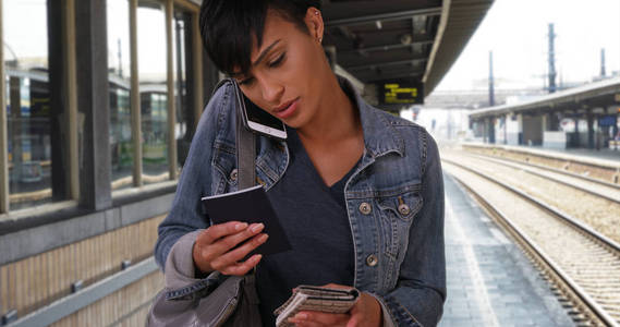 旅行的黑人女性在地铁站等候与智能手机上的护照聊天